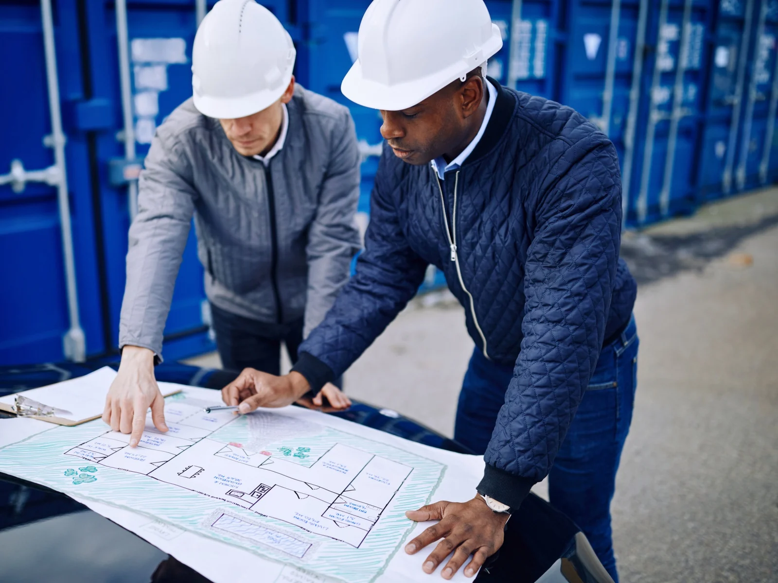 Ingenieros revisando planos técnicos junto a instalaciones industriales