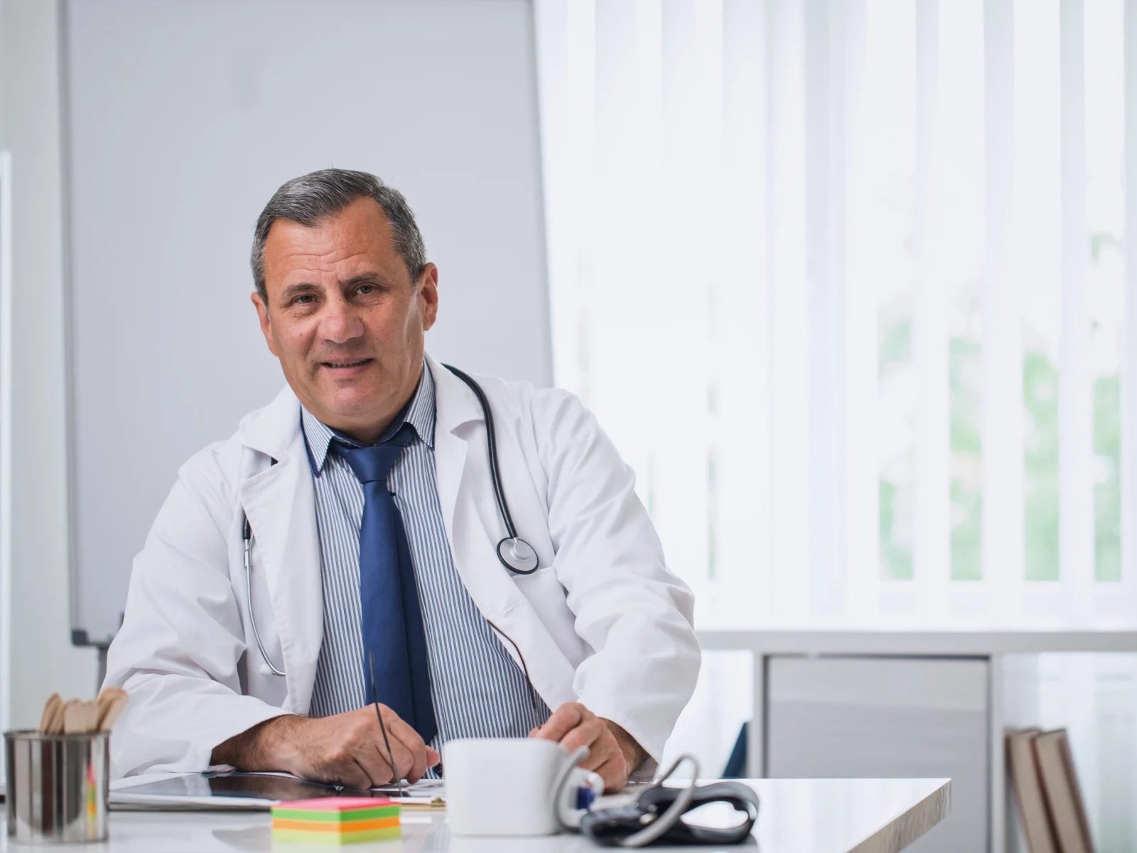 Médico con bata y estetoscopio en consulta